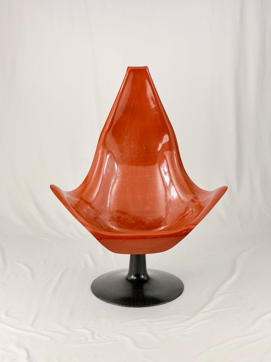 Spage Age fiberglass orange chair with a black base on a white background