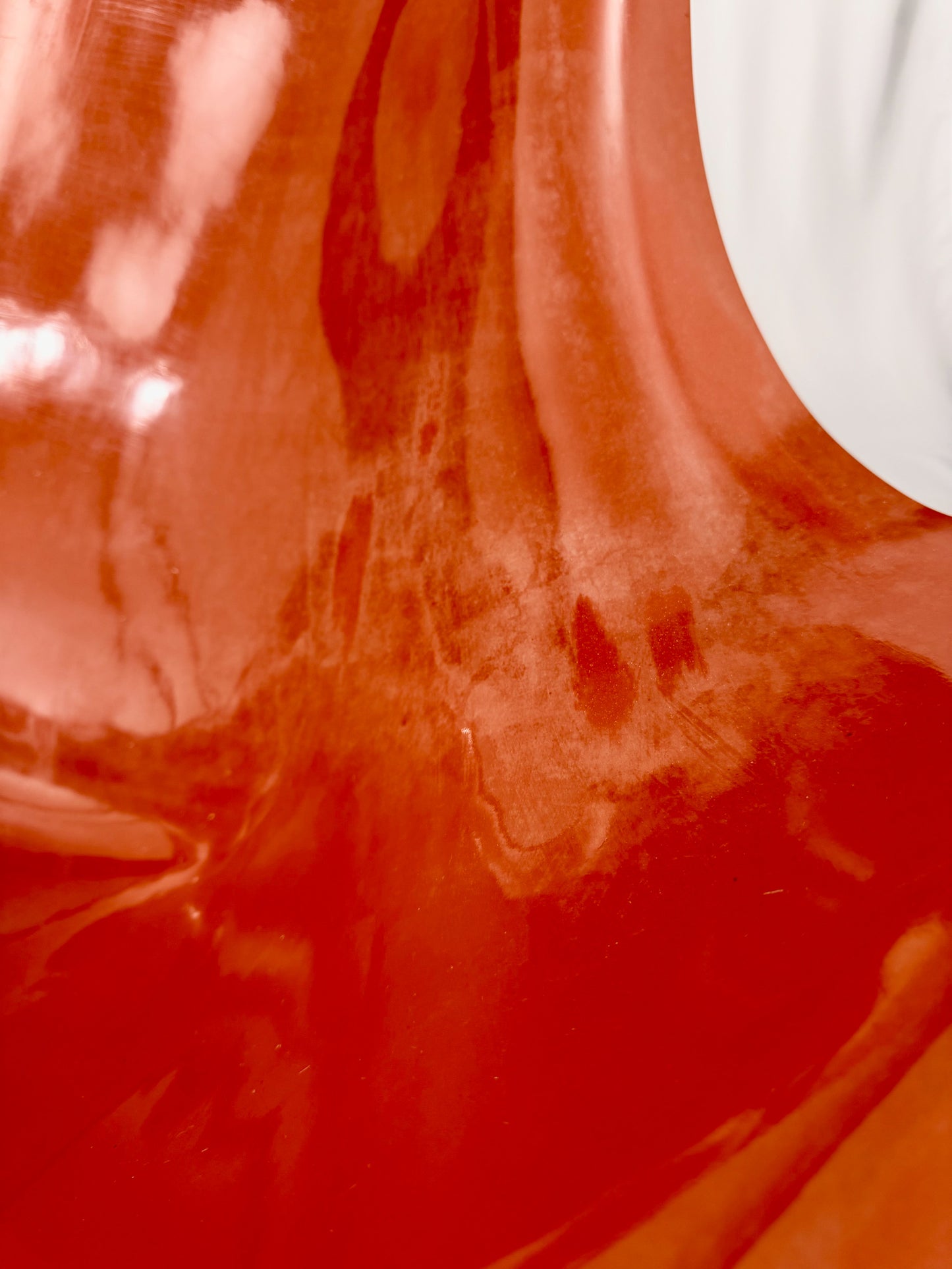 Close up of a Spage Age fiberglass orange chair showing wear marks
