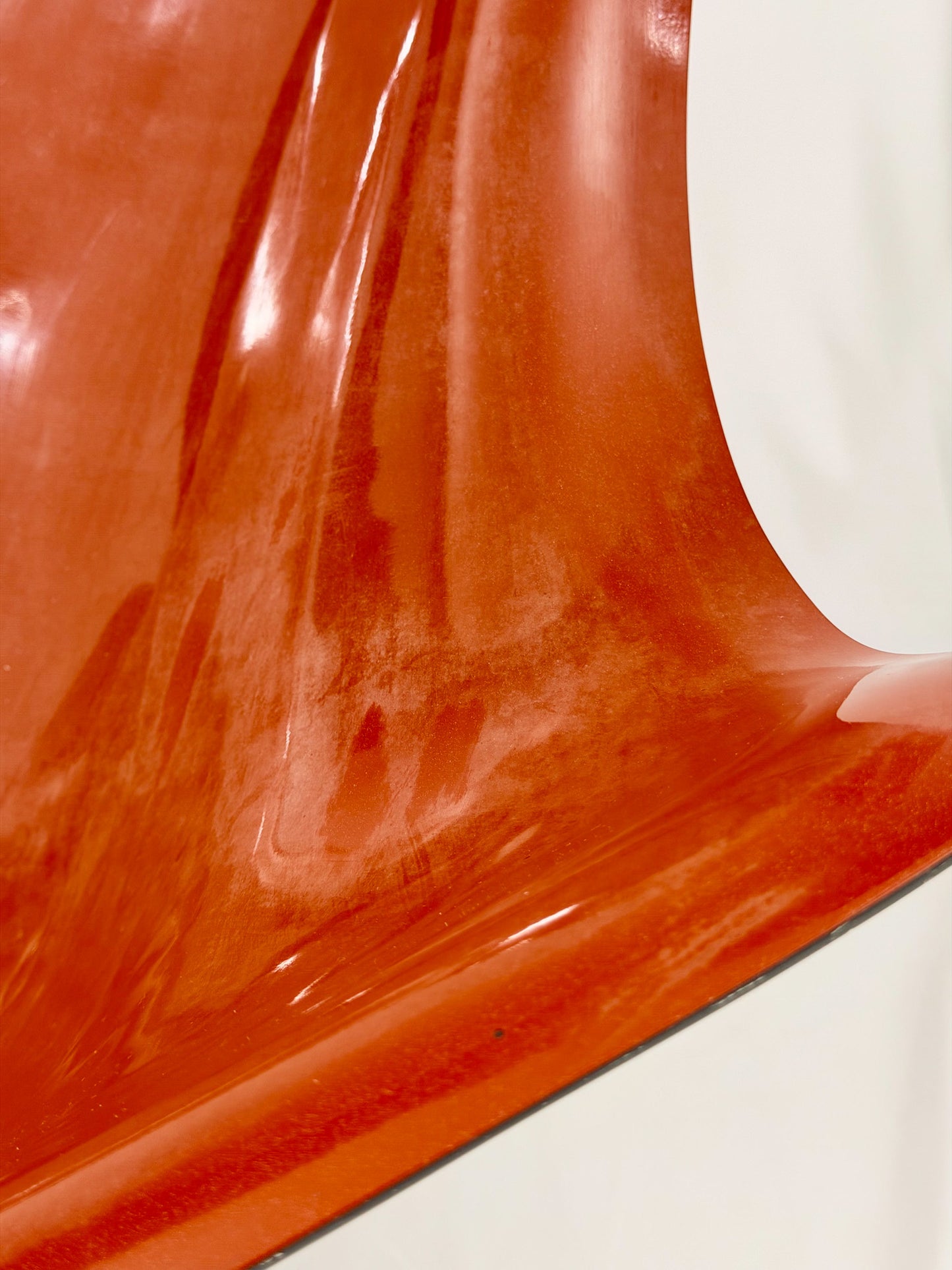Close up of a Spage Age fiberglass orange chair showing wear marks
