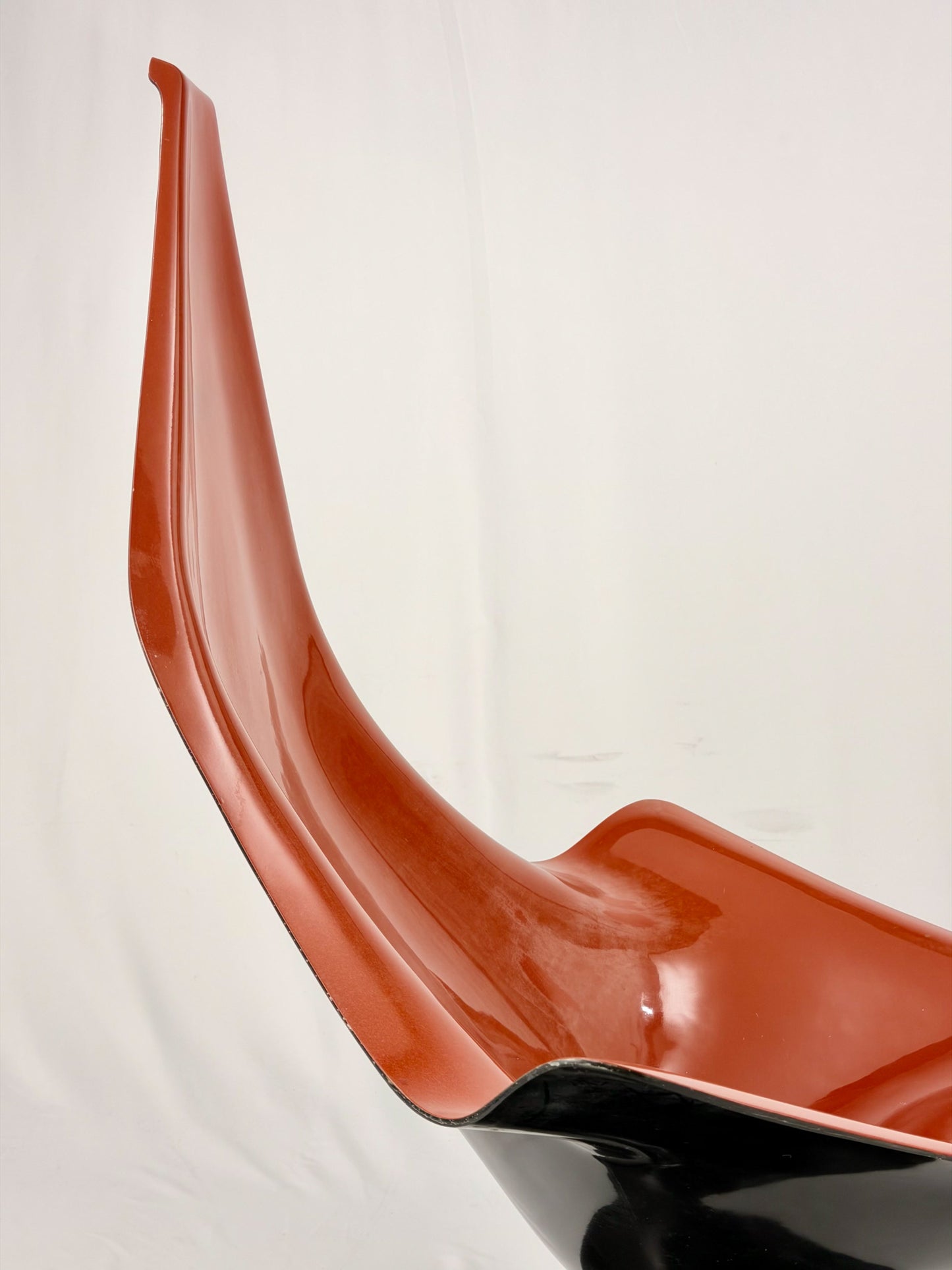 Spage Age fiberglass orange chair with a black base on a white background