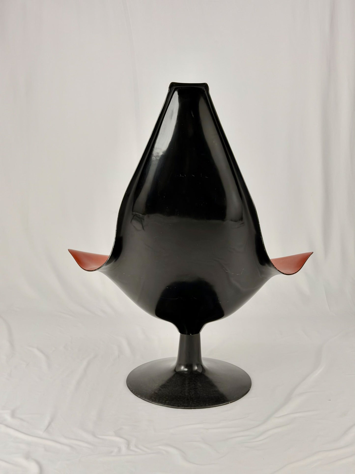 Spage Age fiberglass orange chair with a black base on a white background