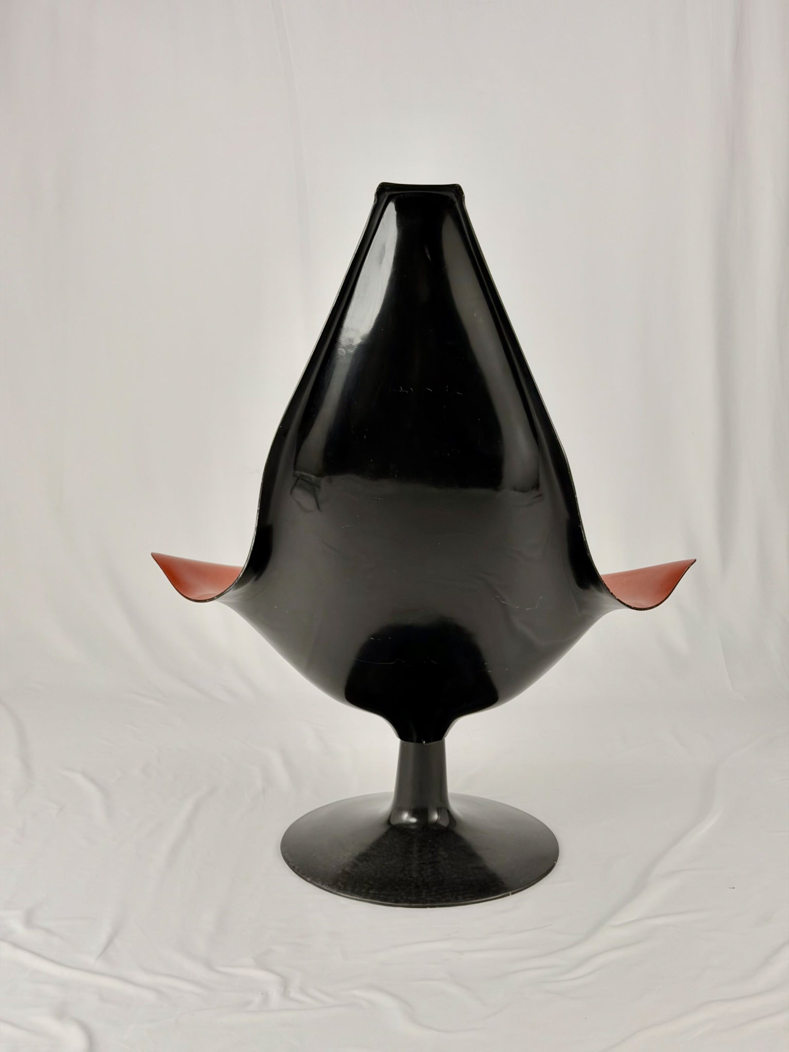 Spage Age fiberglass orange chair with a black base on a white background