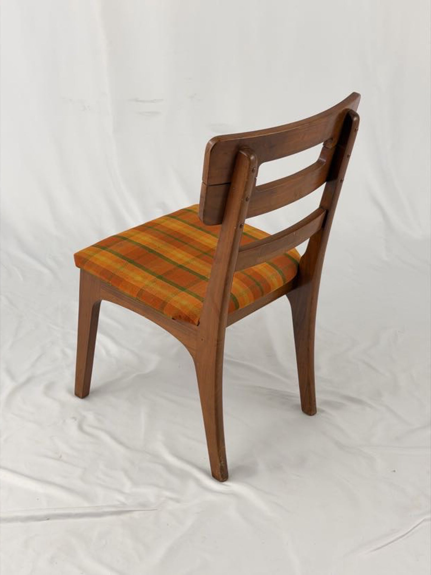 Wooden chair with a striped orange and brown seat on a white background