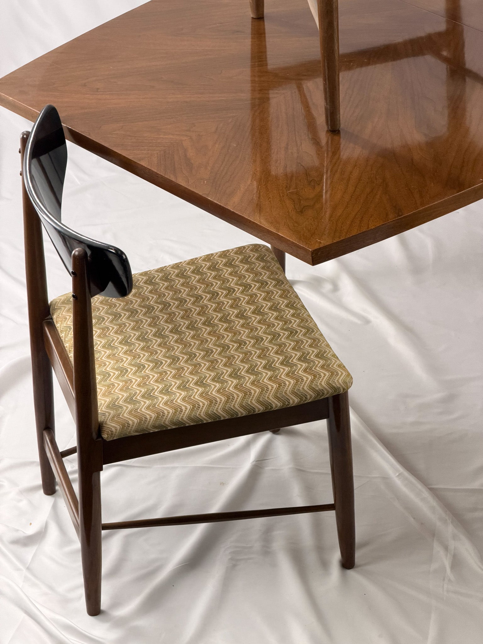 Wooden chair with patterned cushion on a white fabric background