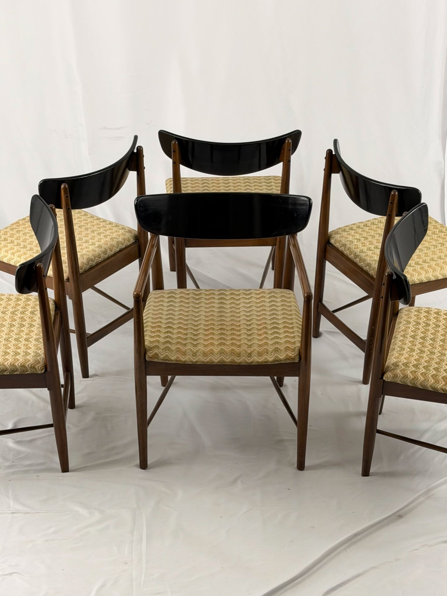 Set of six wooden chairs with upholstered seats on a white background