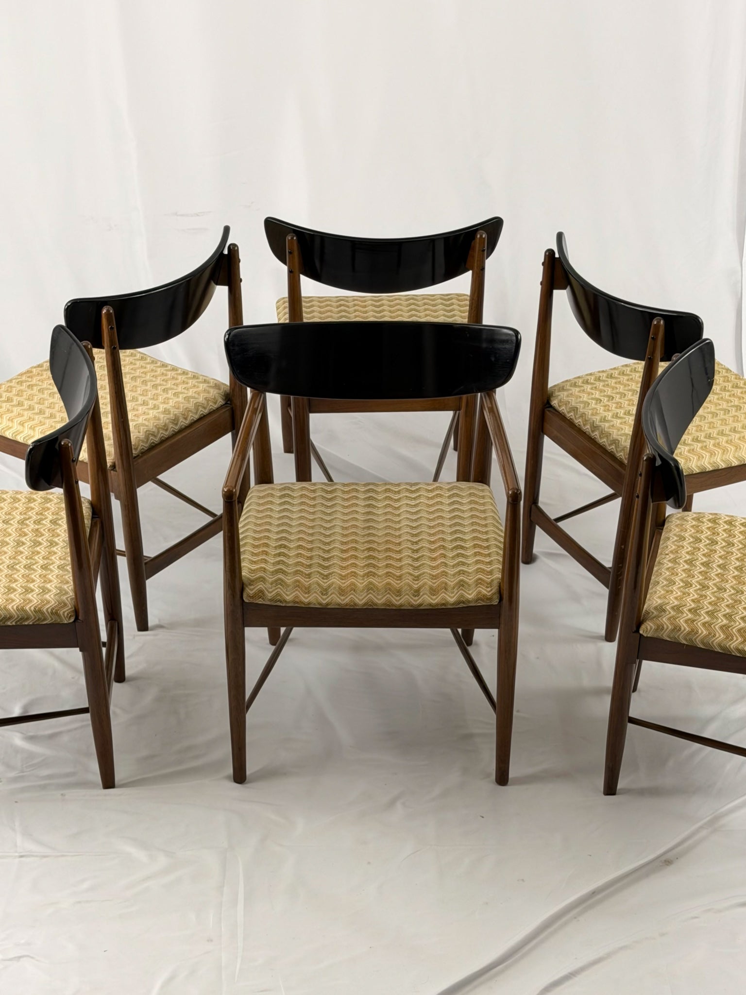 Set of six wooden chairs with upholstered seats on a white background