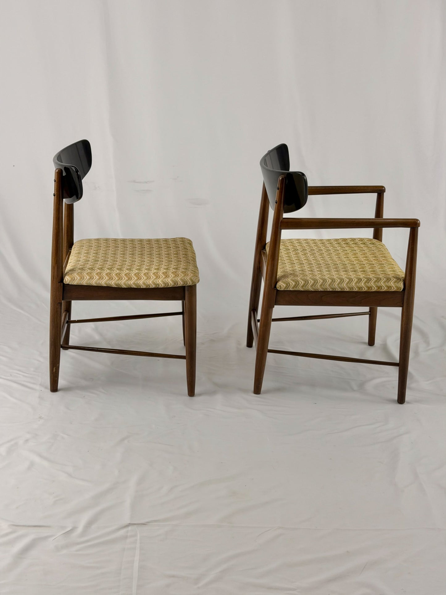 Two wooden chairs with upholstered seats on a white background