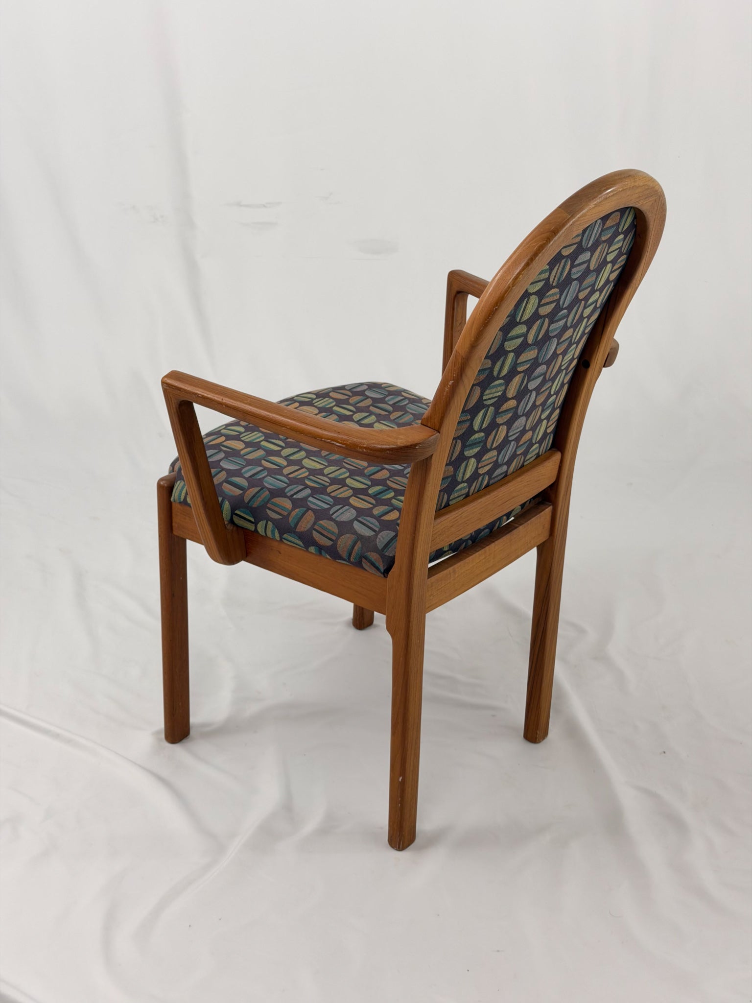 Wooden chair with patterned fabric seat and backrest on a white background
