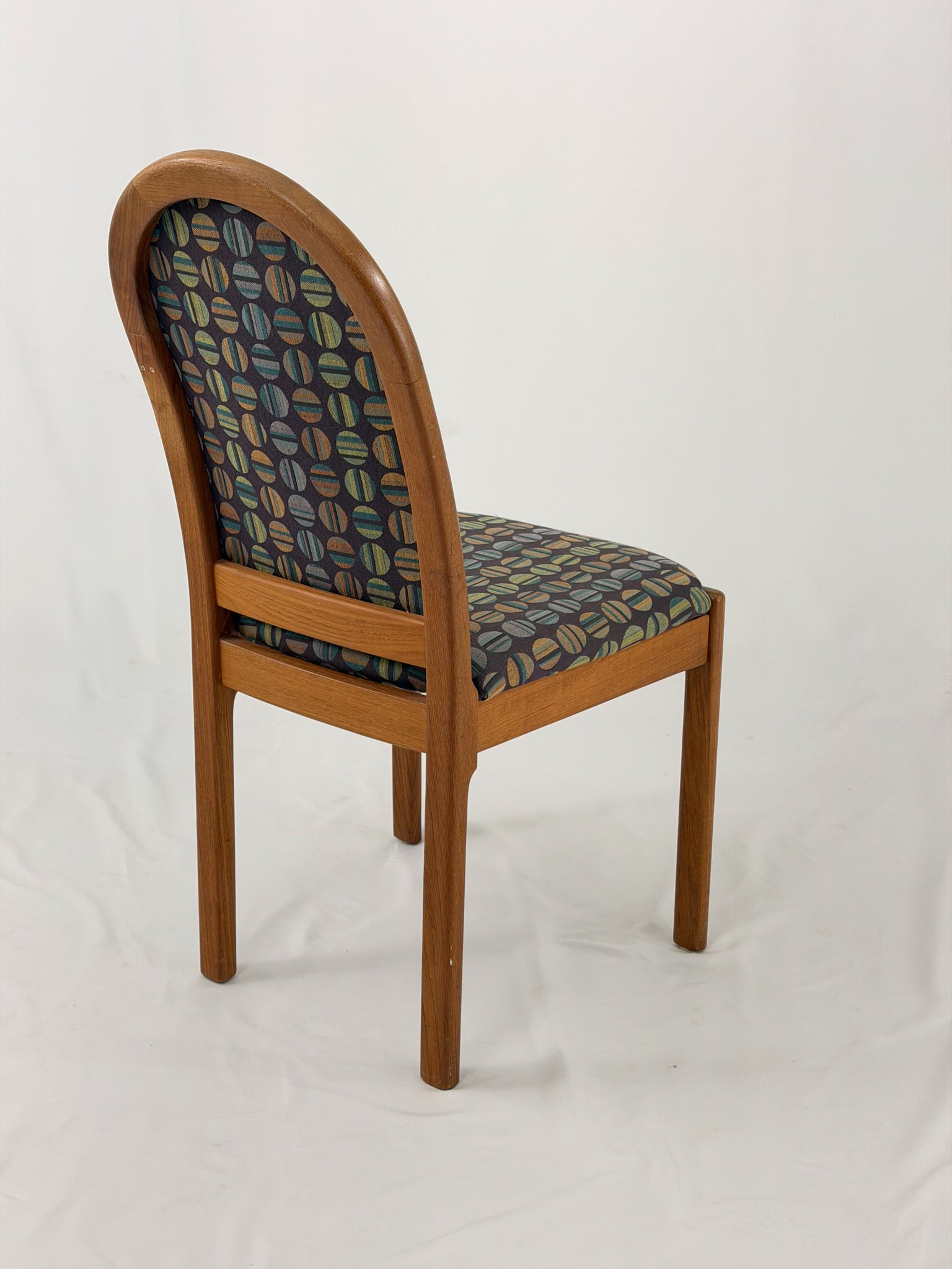 Wooden chair with patterned fabric seat and backrest on a white background