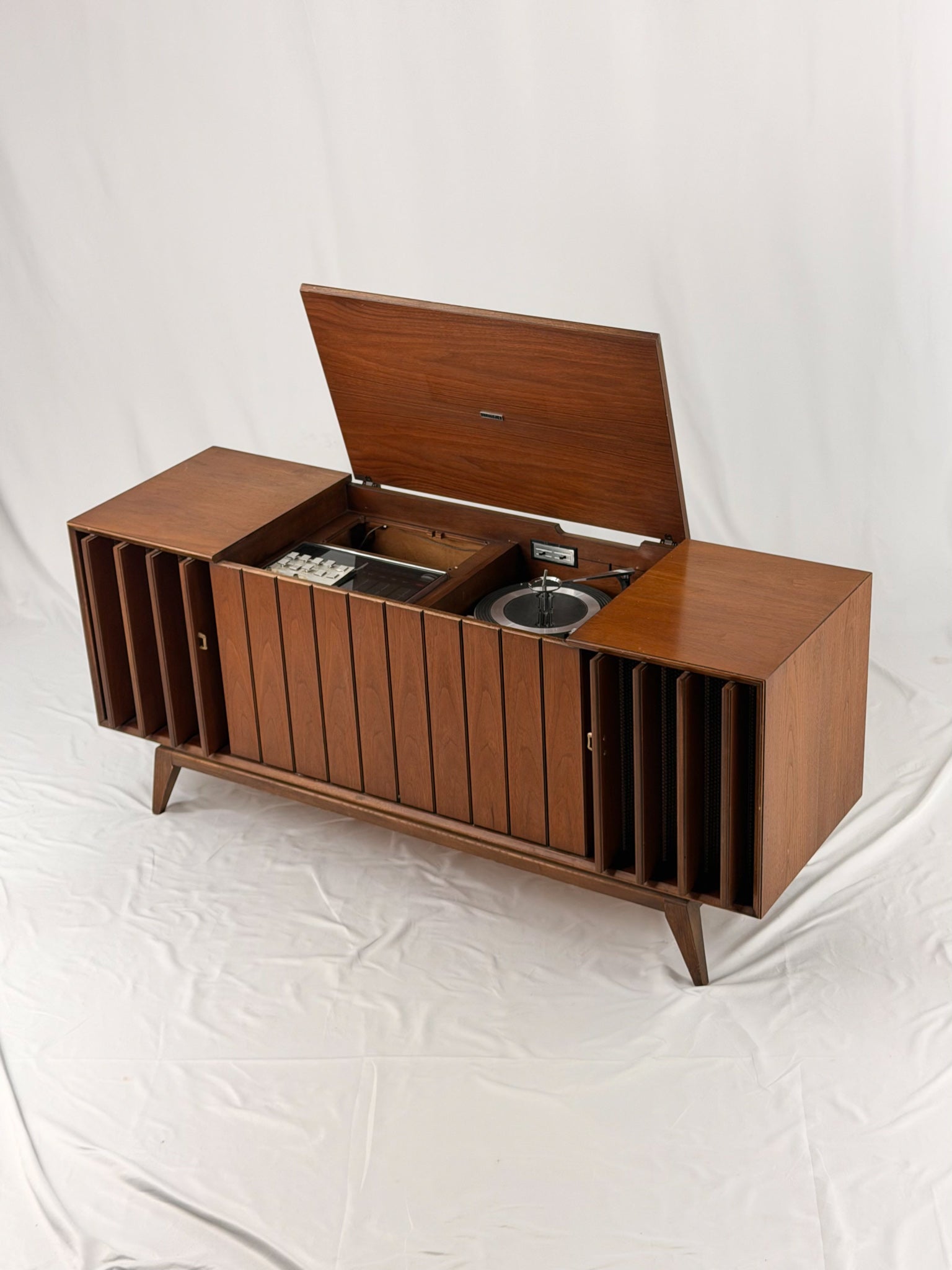 Vintage record player with a turntable and control panel on a wooden surface.
