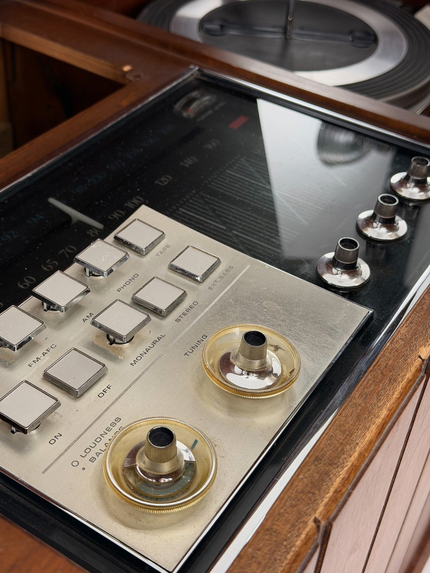 Vintage record player with a turntable and control panel on a wooden surface.