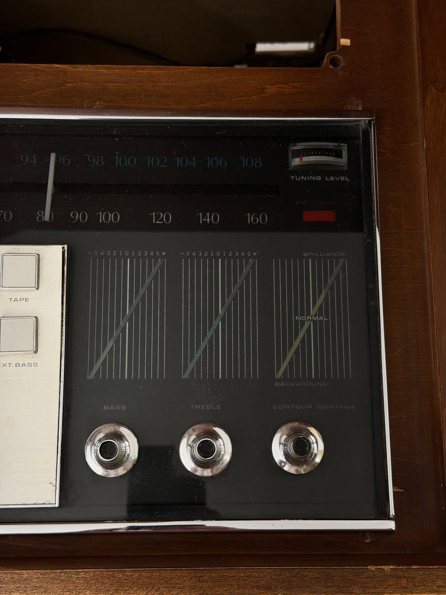 Vintage radio receiver with control knobs and display on a wooden cabinet.