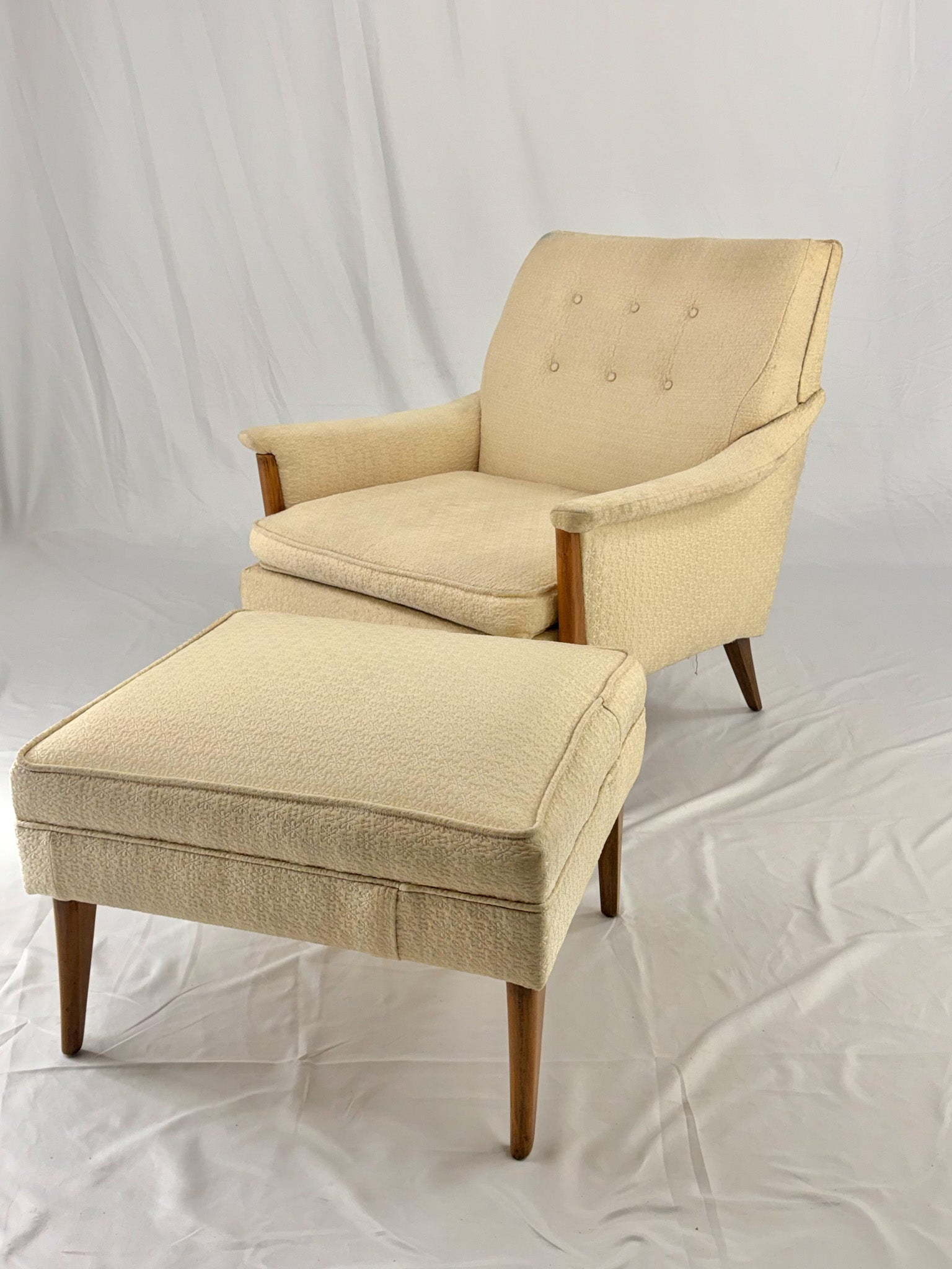 Beige armchair with matching ottoman on a white background