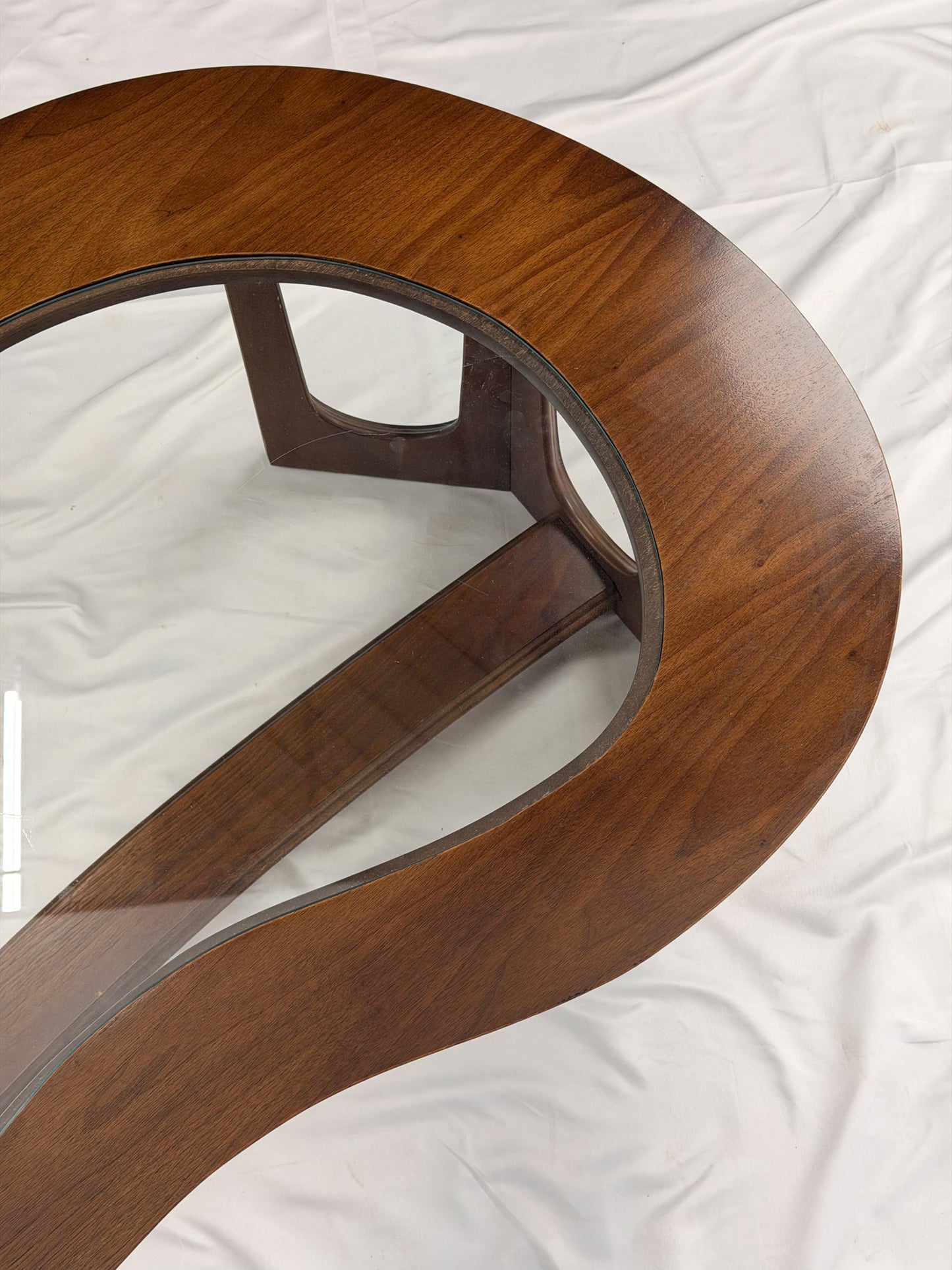 Wooden kidney shaped coffee table with a glass top on a white background