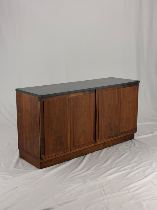 Wooden sideboard with a black countertop on a plain background