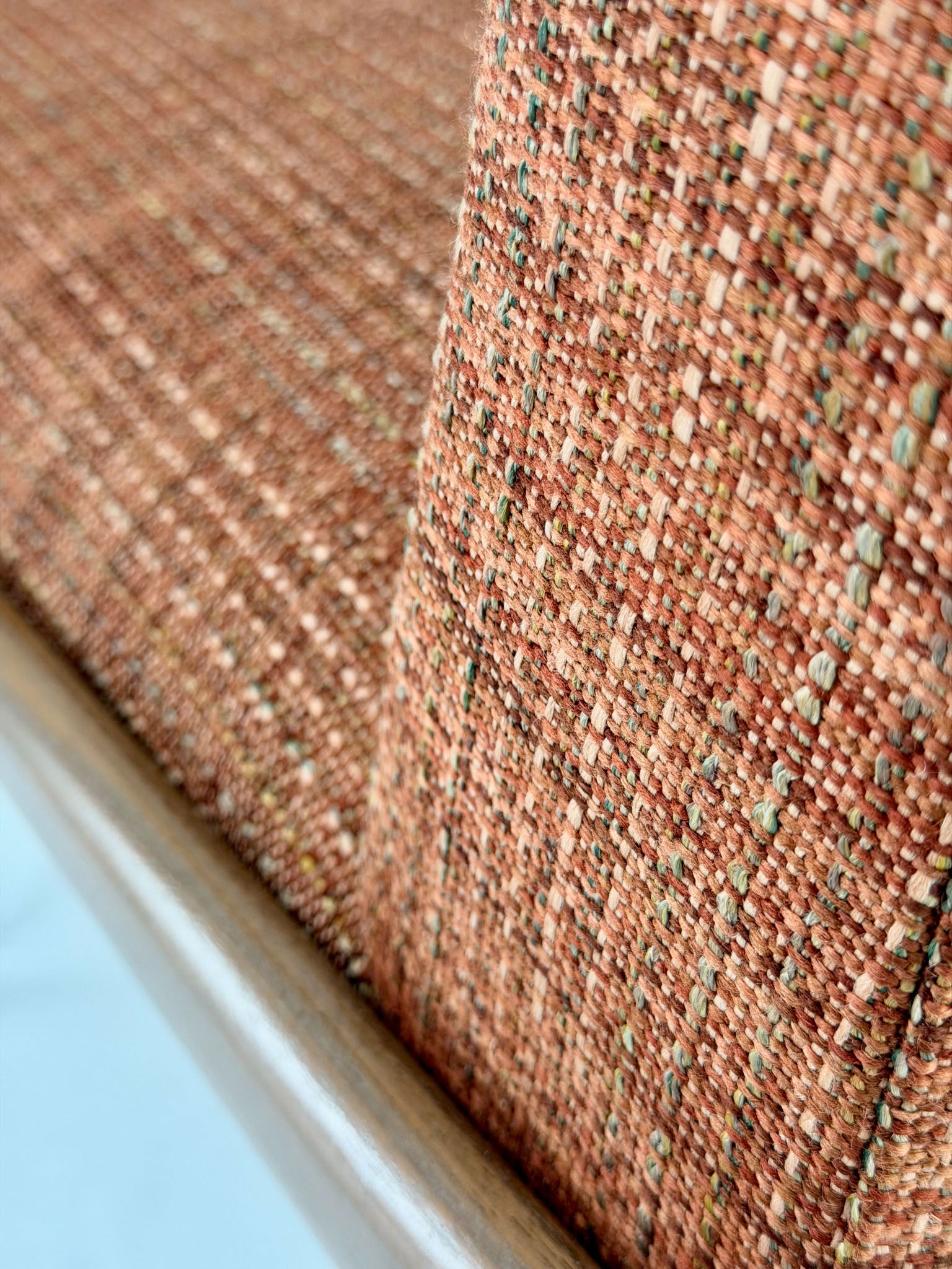 Close-up of a chair with wooden legs and a orange fabric seat on a white background