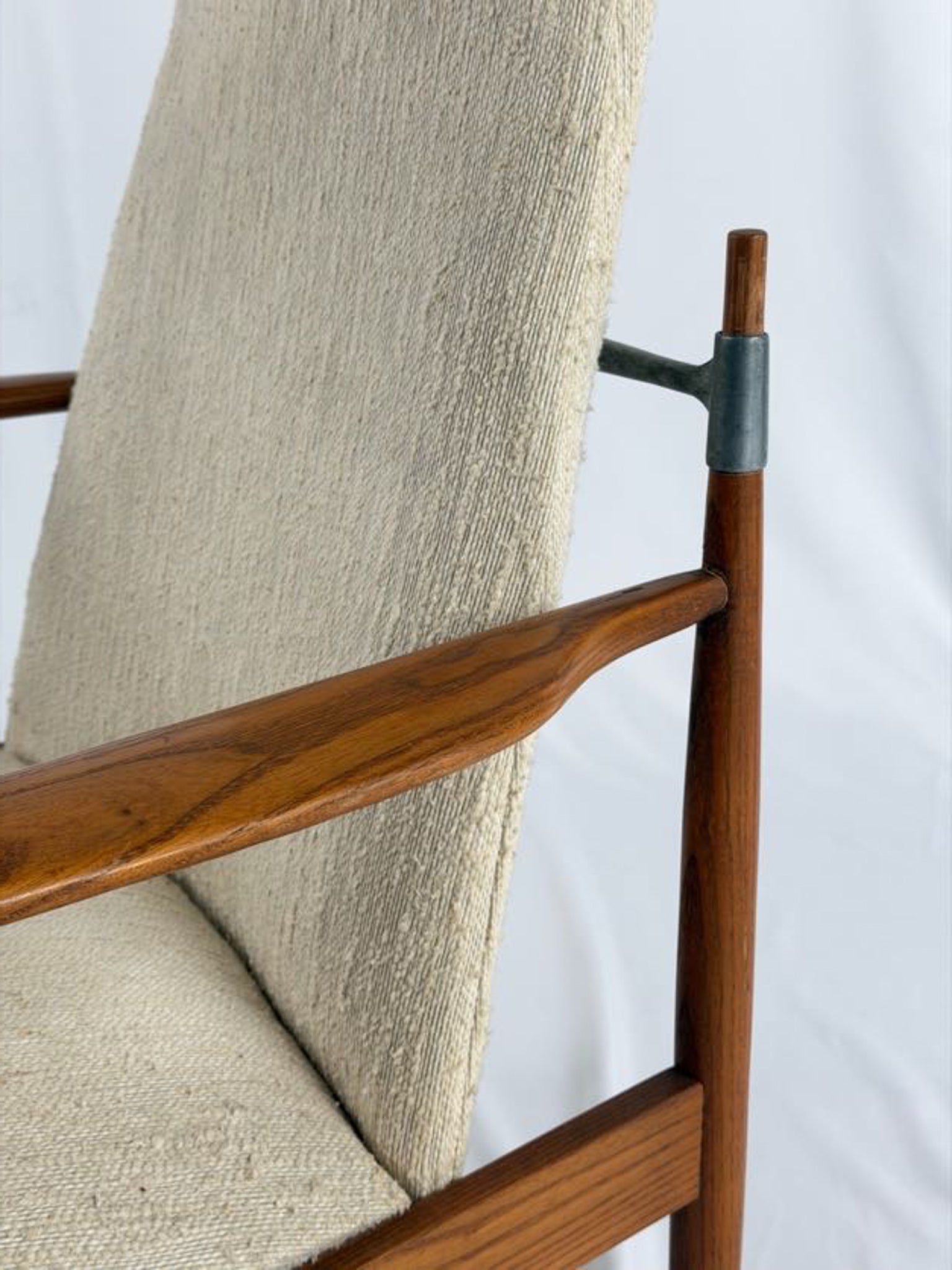 Close-up of a wooden chair with beige fabric backrest and seat on a white background