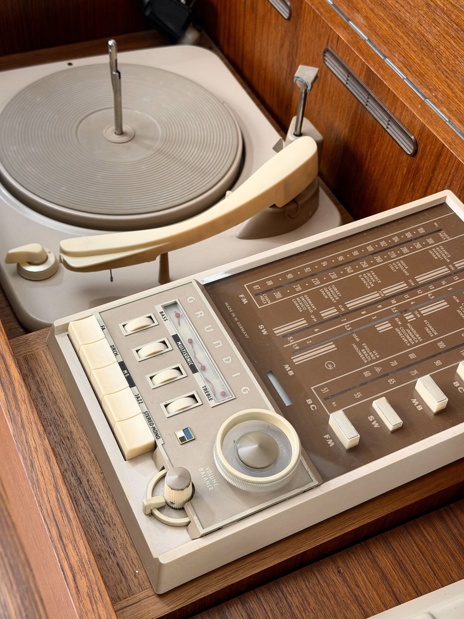 Vintage record player with a turntable and control panel on a wooden surface.