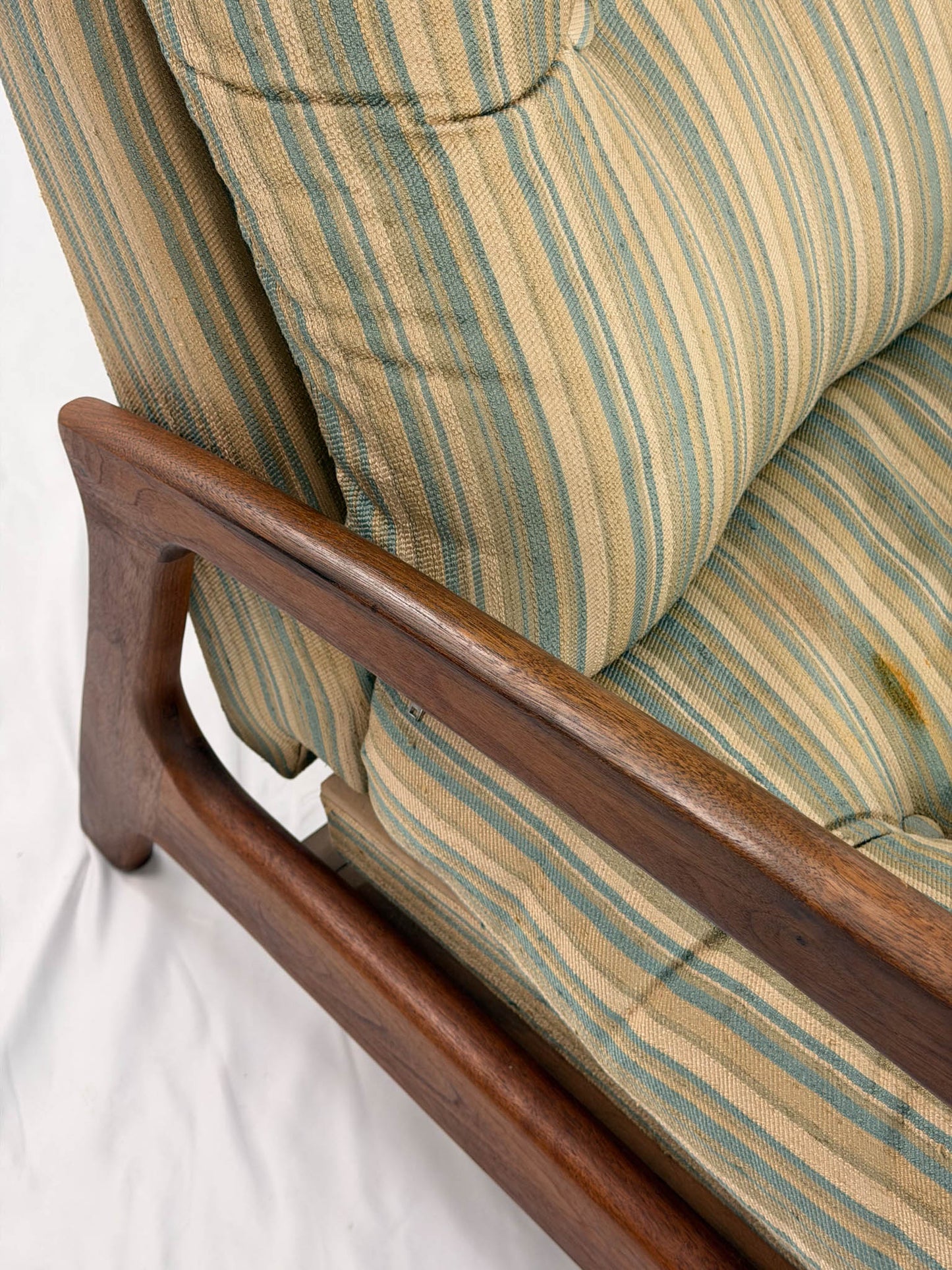 Close-up of a striped cushioned chair with wooden armrests on a white background