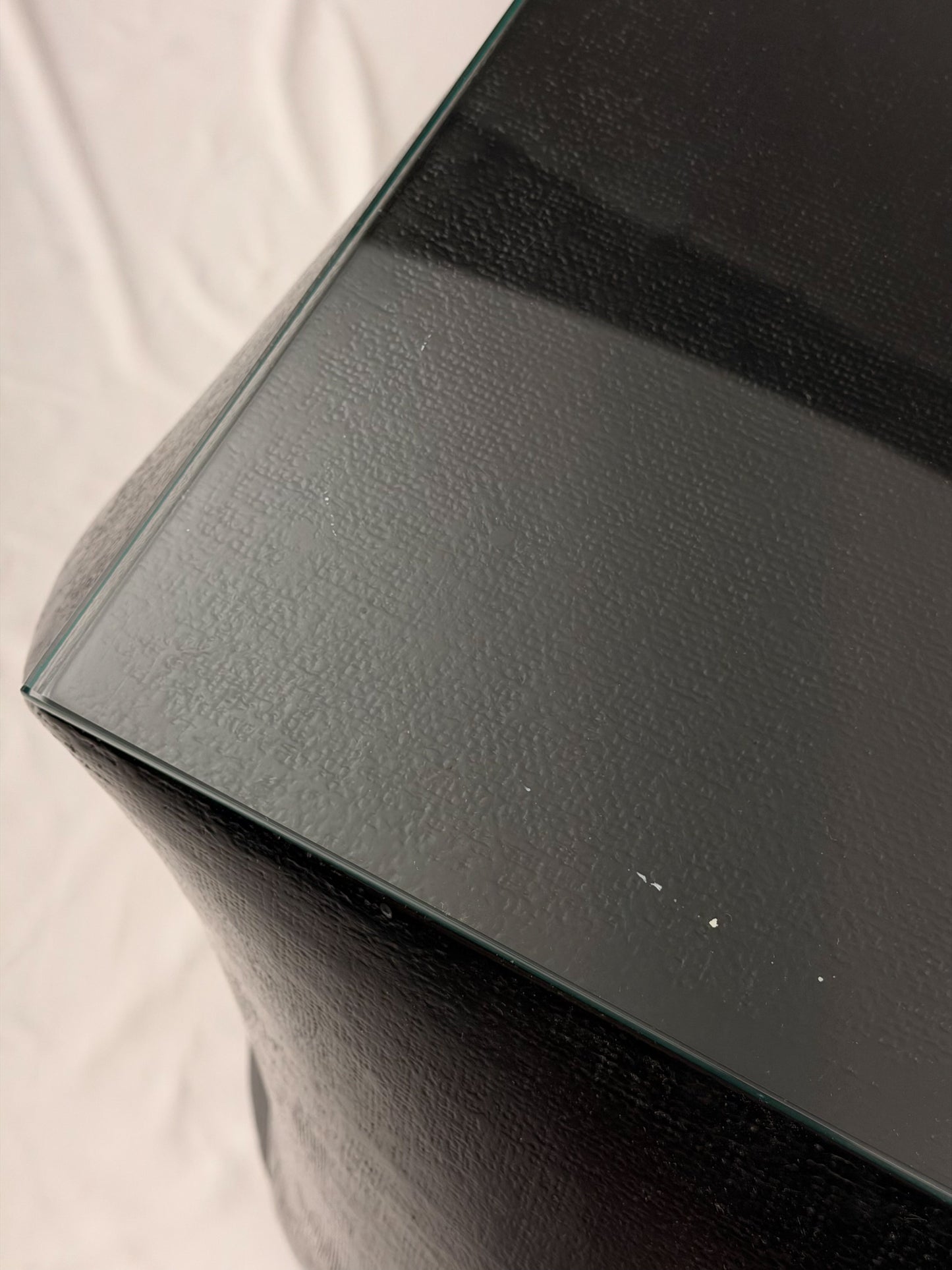 Two geometric black side tables on a white fabric background