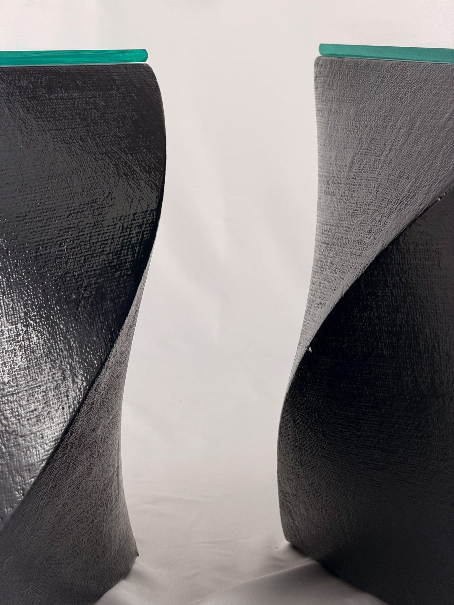 Two geometric black side tables on a white fabric background