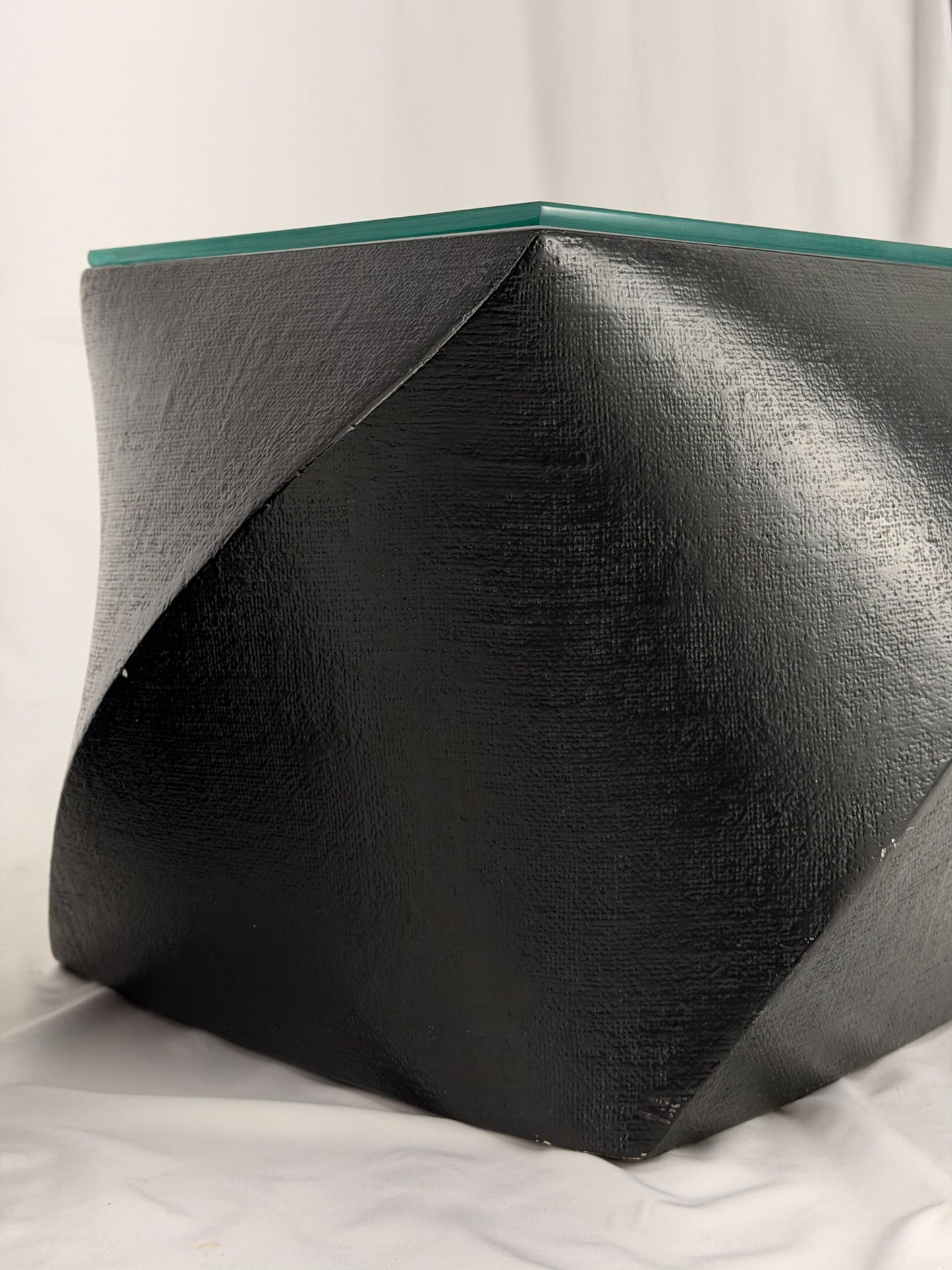Two geometric black side tables on a white fabric background