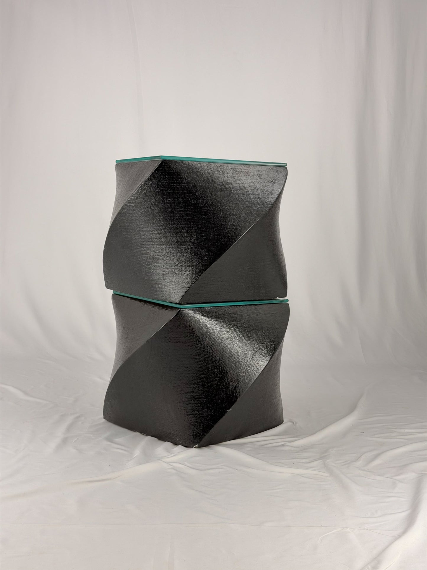 Two geometric black side tables on a white fabric background