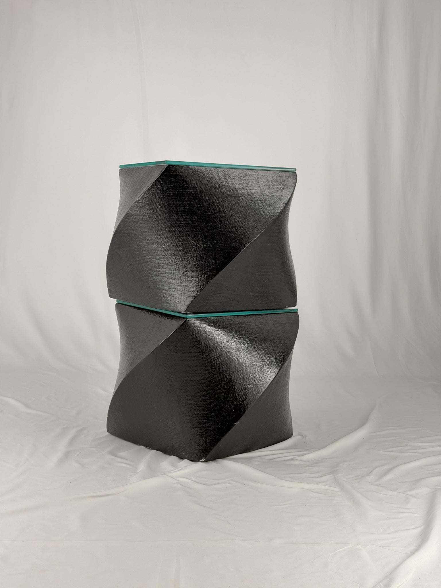 Two geometric black side tables on a white fabric background