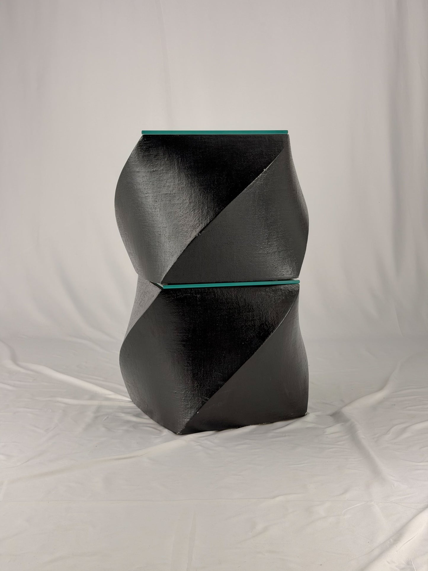 Two geometric black side tables on a white fabric background