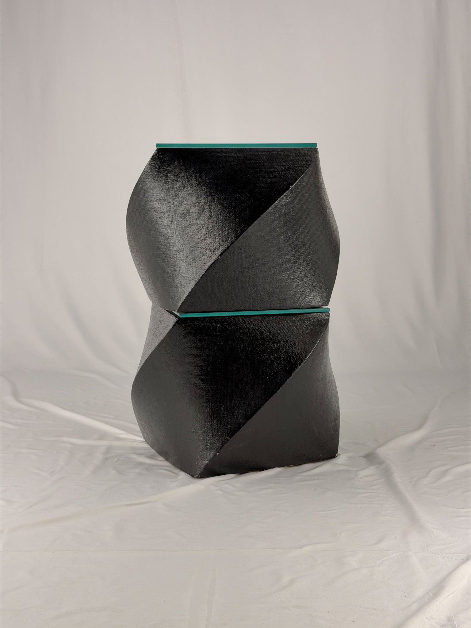 Two geometric black side tables on a white fabric background