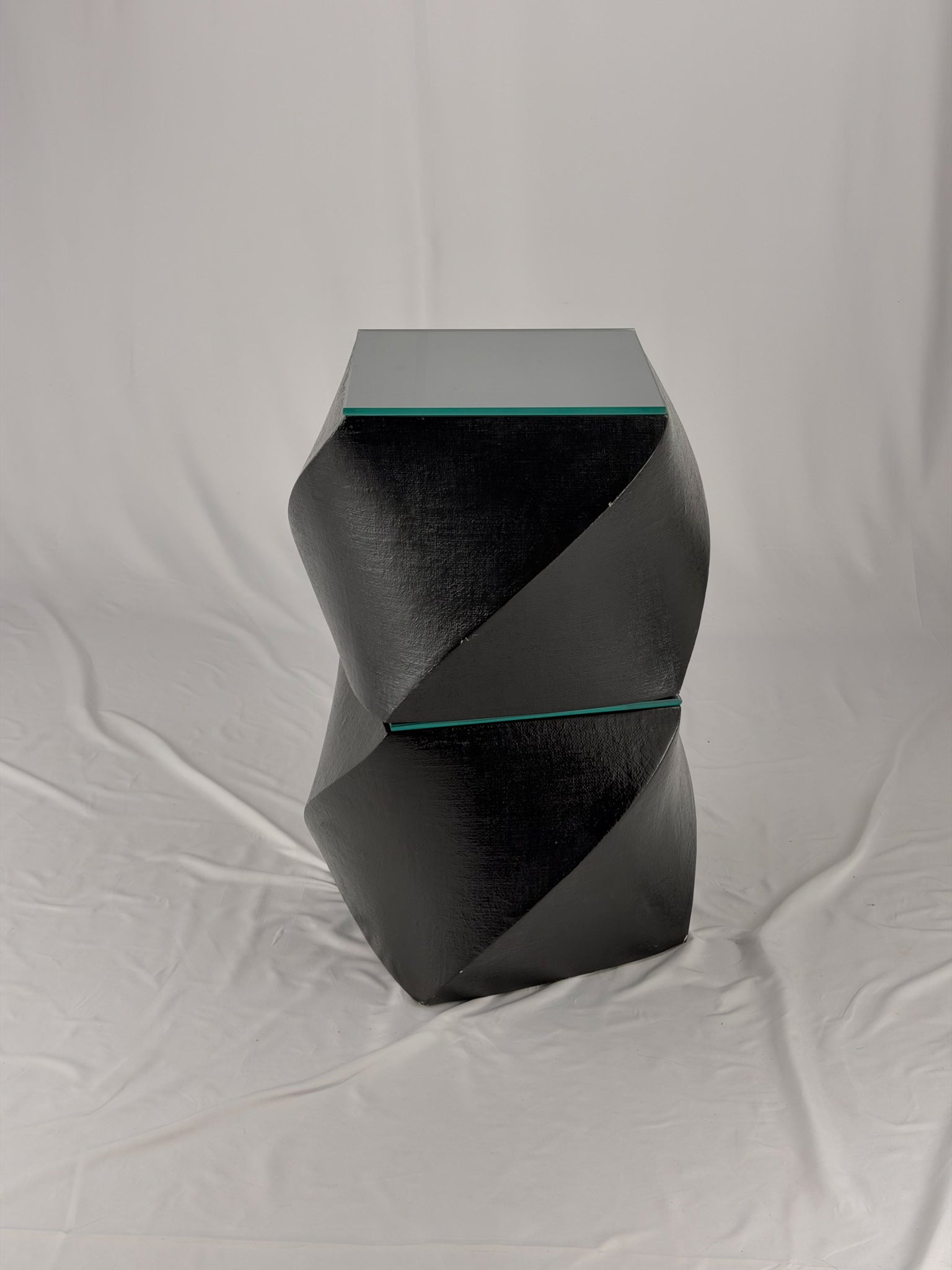 Two geometric black side tables on a white fabric background