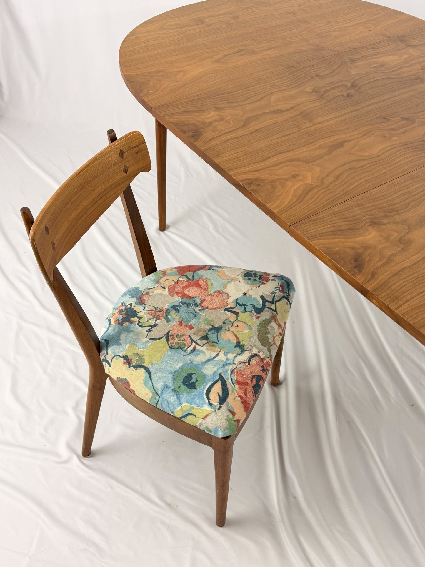 Wooden chair with floral cushion next to a wooden table on a white background