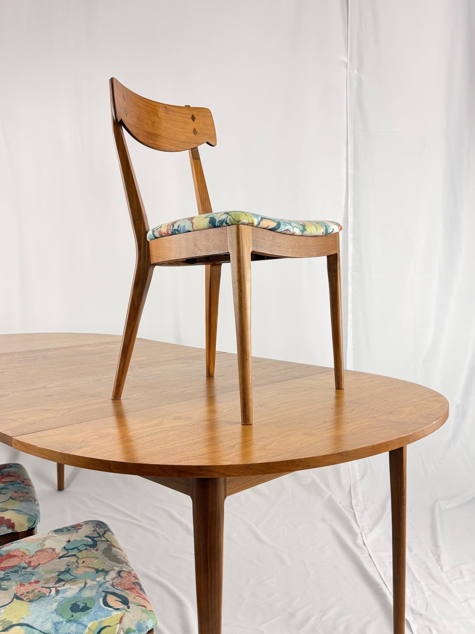 Wooden chair with a floral cushion on a wooden table against a white background