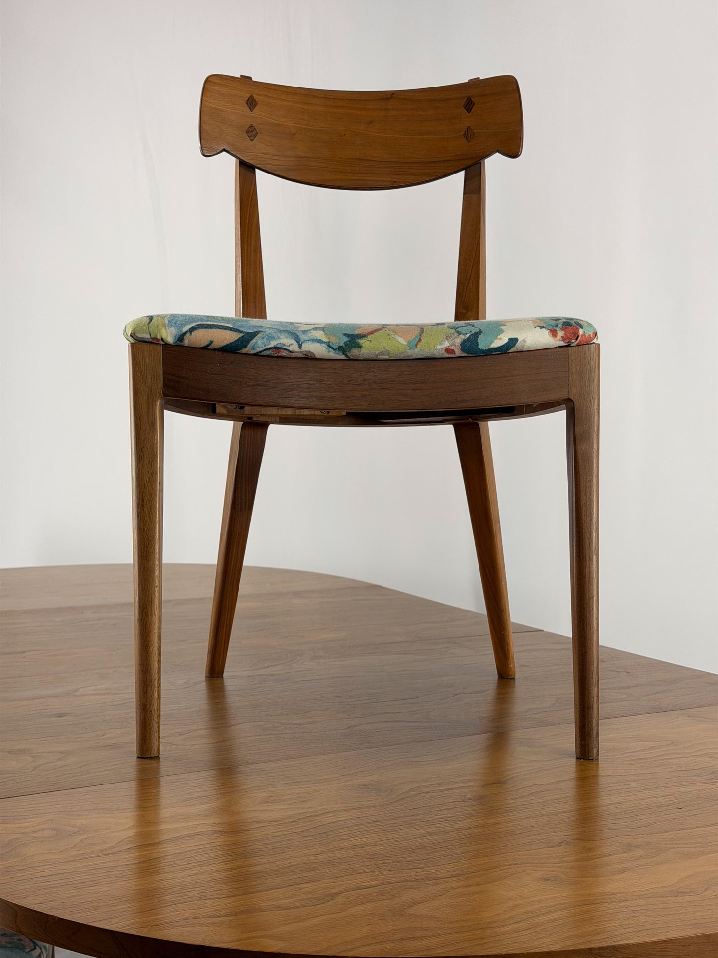Wooden chair with a patterned cushion on a wooden floor against a white wall