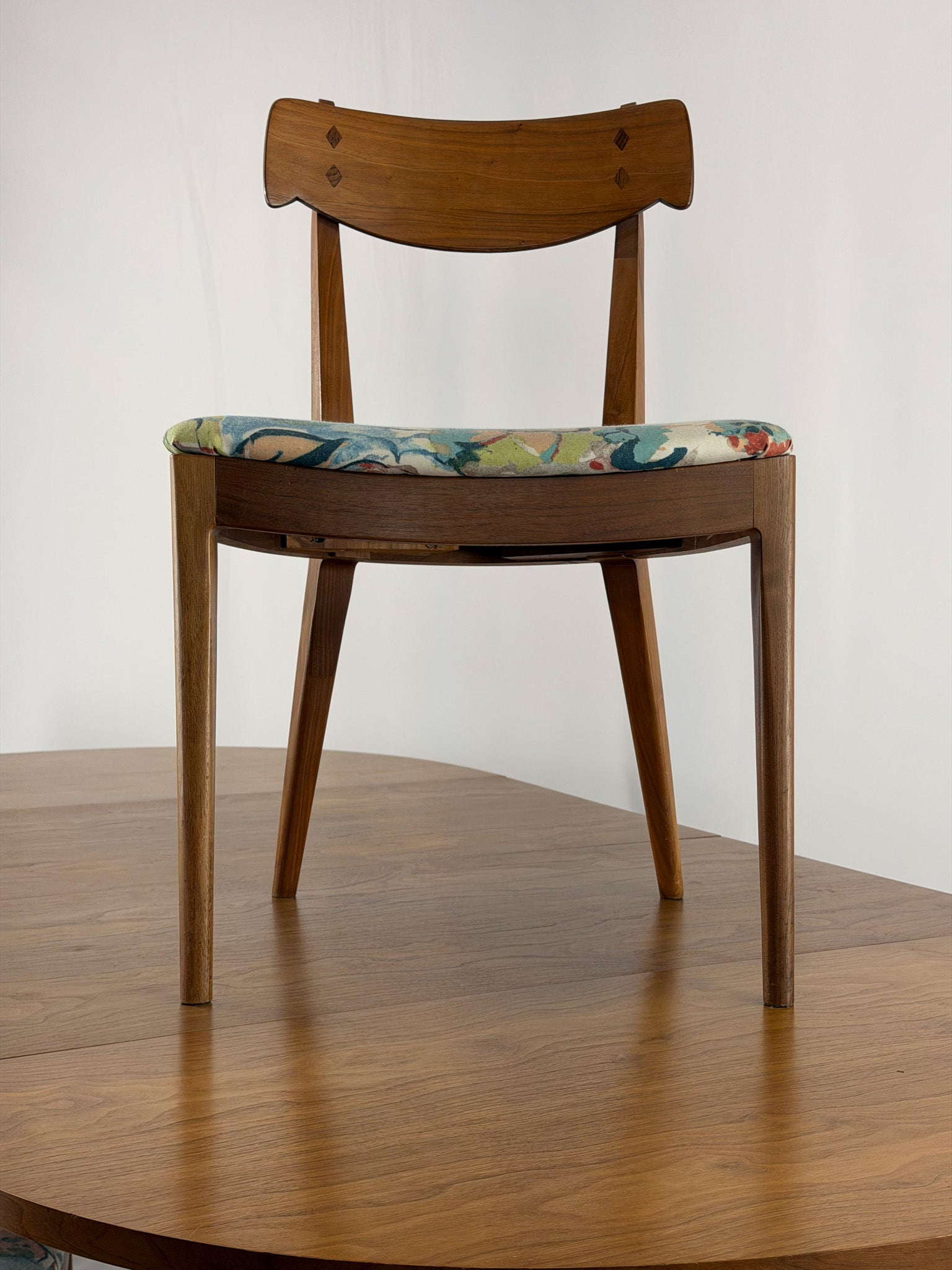 Wooden chair with a patterned cushion on a wooden floor against a white wall