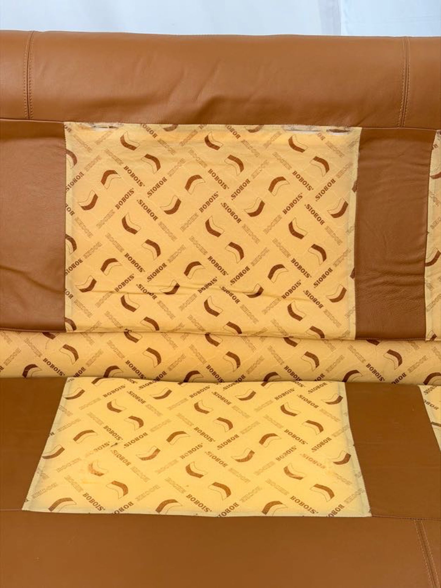 Brown leather sofa with a patterned cushion on a white background