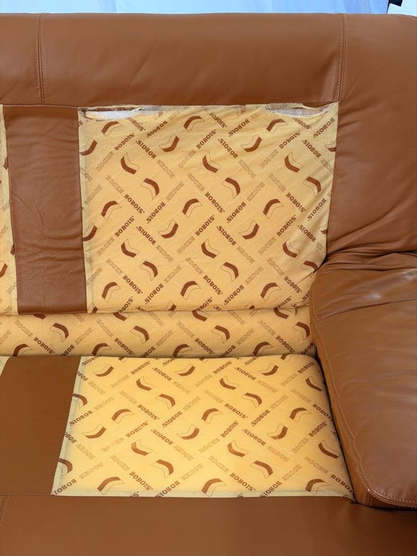 Brown leather sofa with a patterned cushion on a light blue background