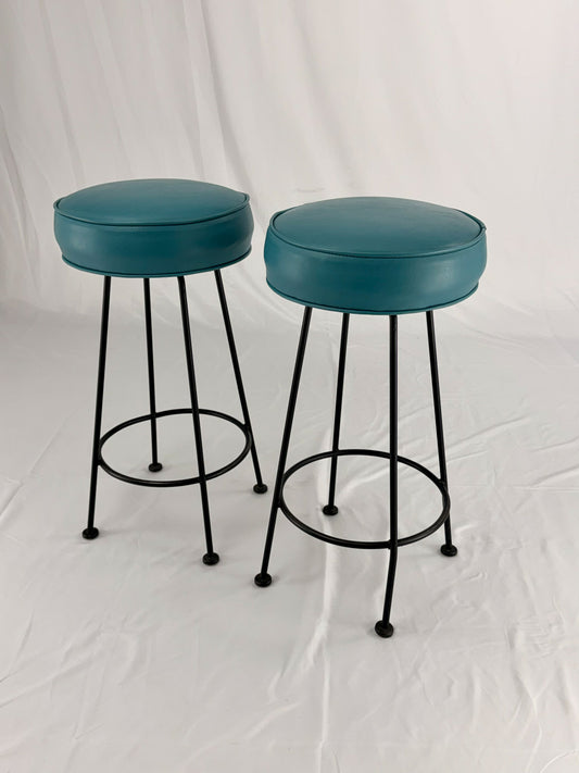Two teal bar stools with black metal legs on a white background