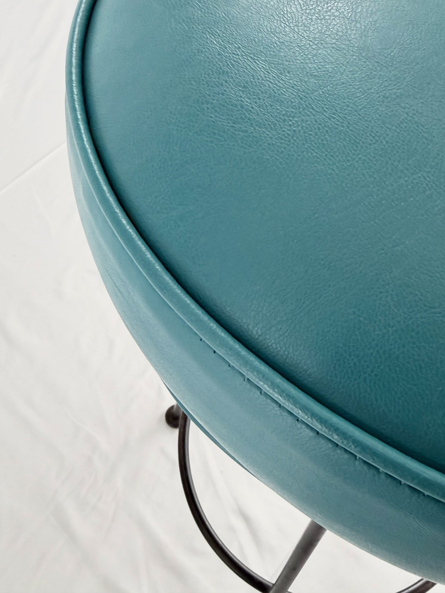 Two teal bar stools with black metal legs on a white background