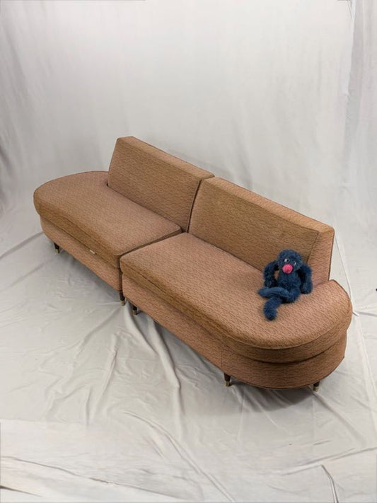 Pink sectional sofa with a blue plush toy on a white background