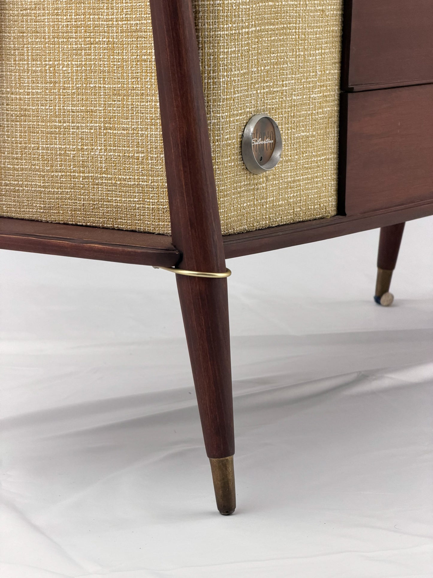 Close-up of a vintage-style radio with wooden casing and brass accents on a white background