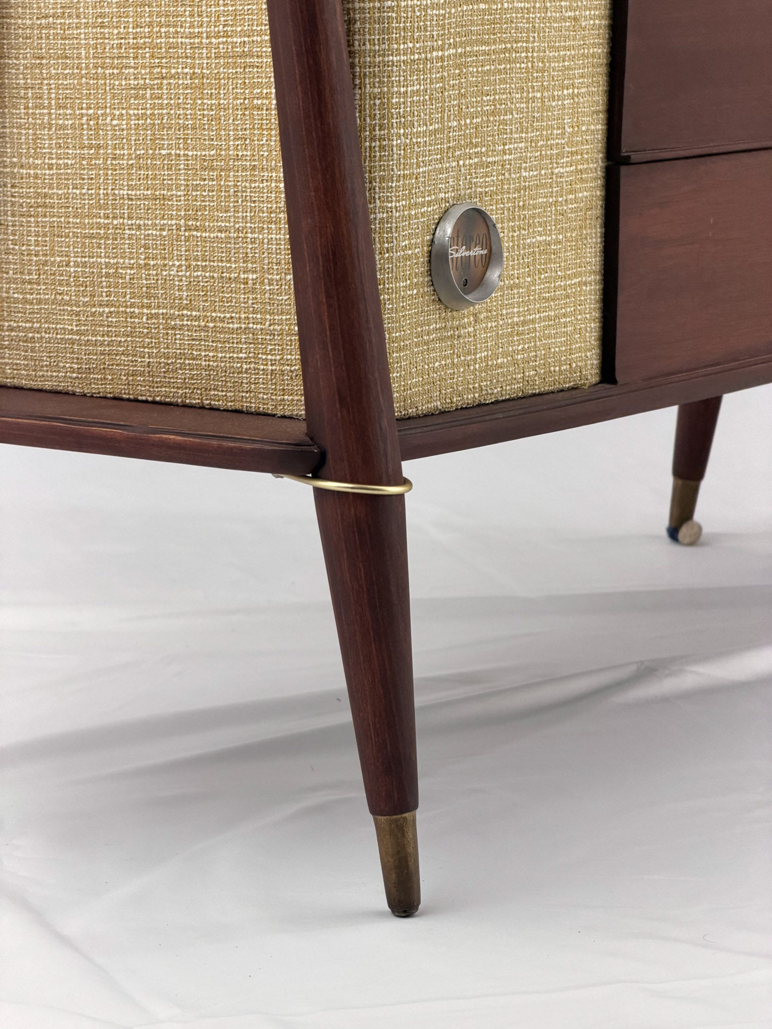 Close-up of a vintage-style radio with wooden casing and brass accents on a white background