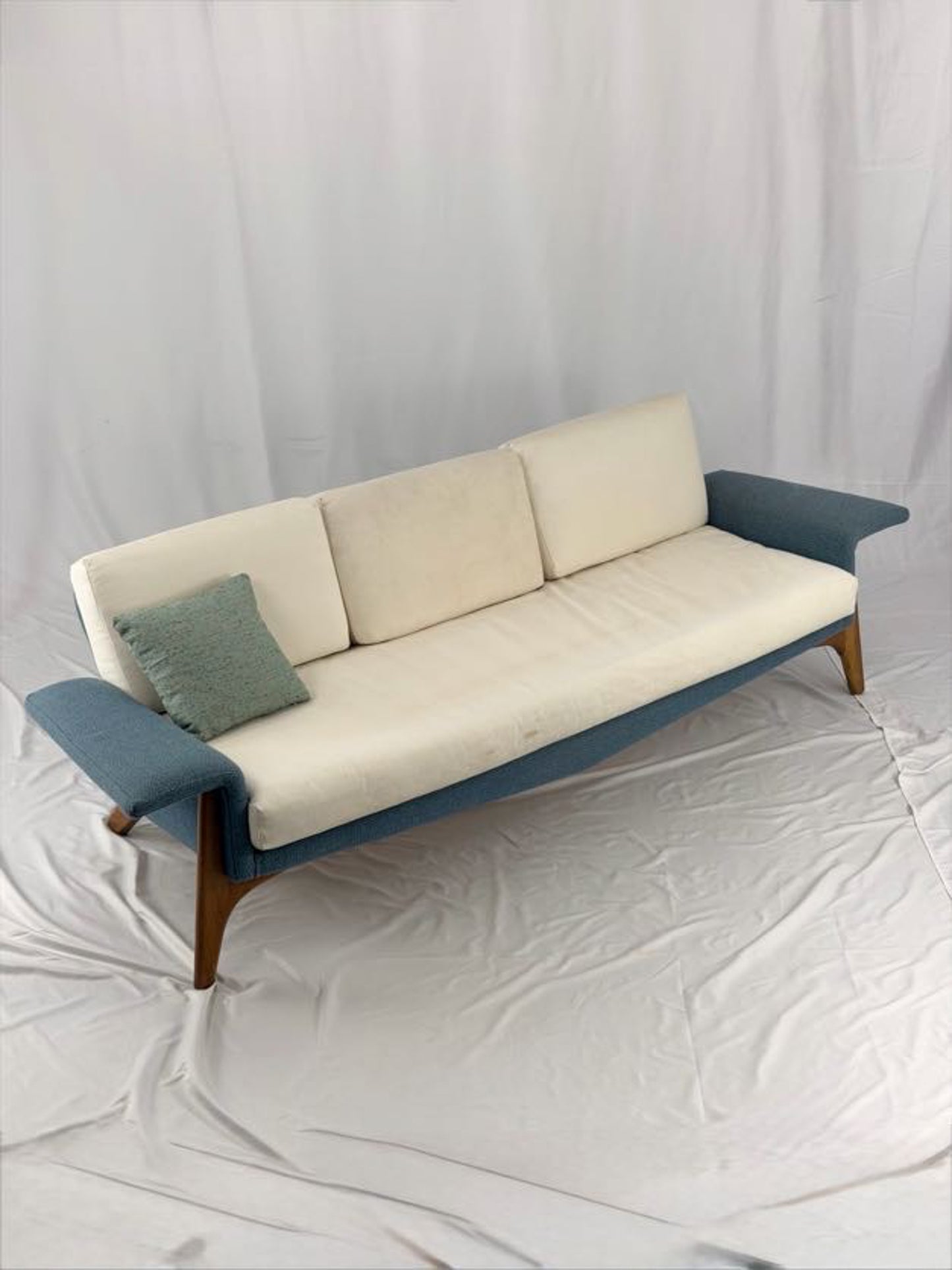 Sofa with blue armrests and beige cushions on a white background