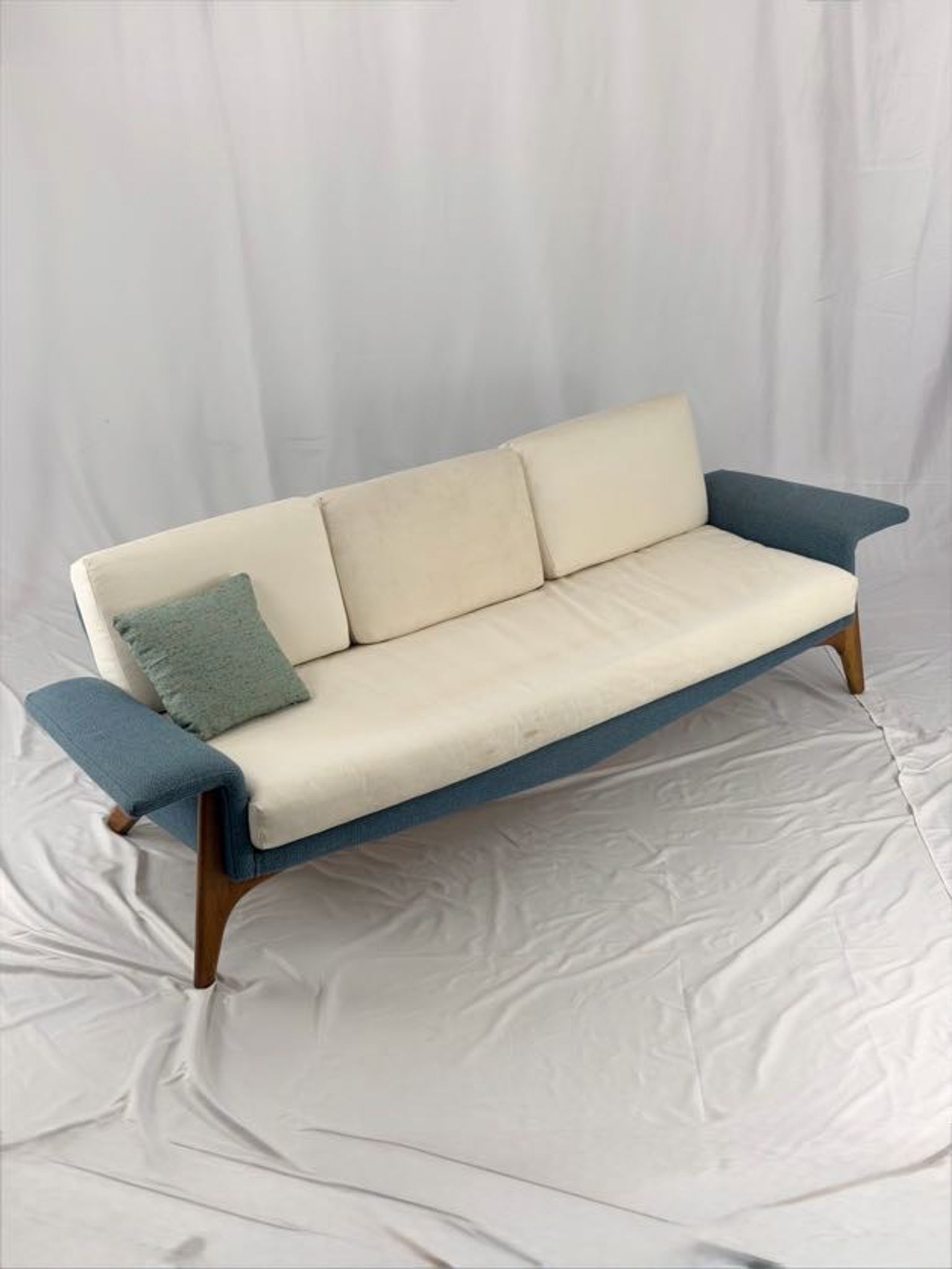 Sofa with blue armrests and beige cushions on a white background