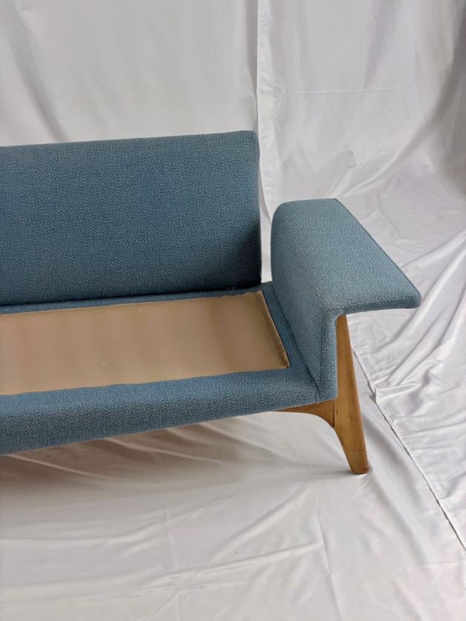 Blue upholstered bench with wooden legs on a white background