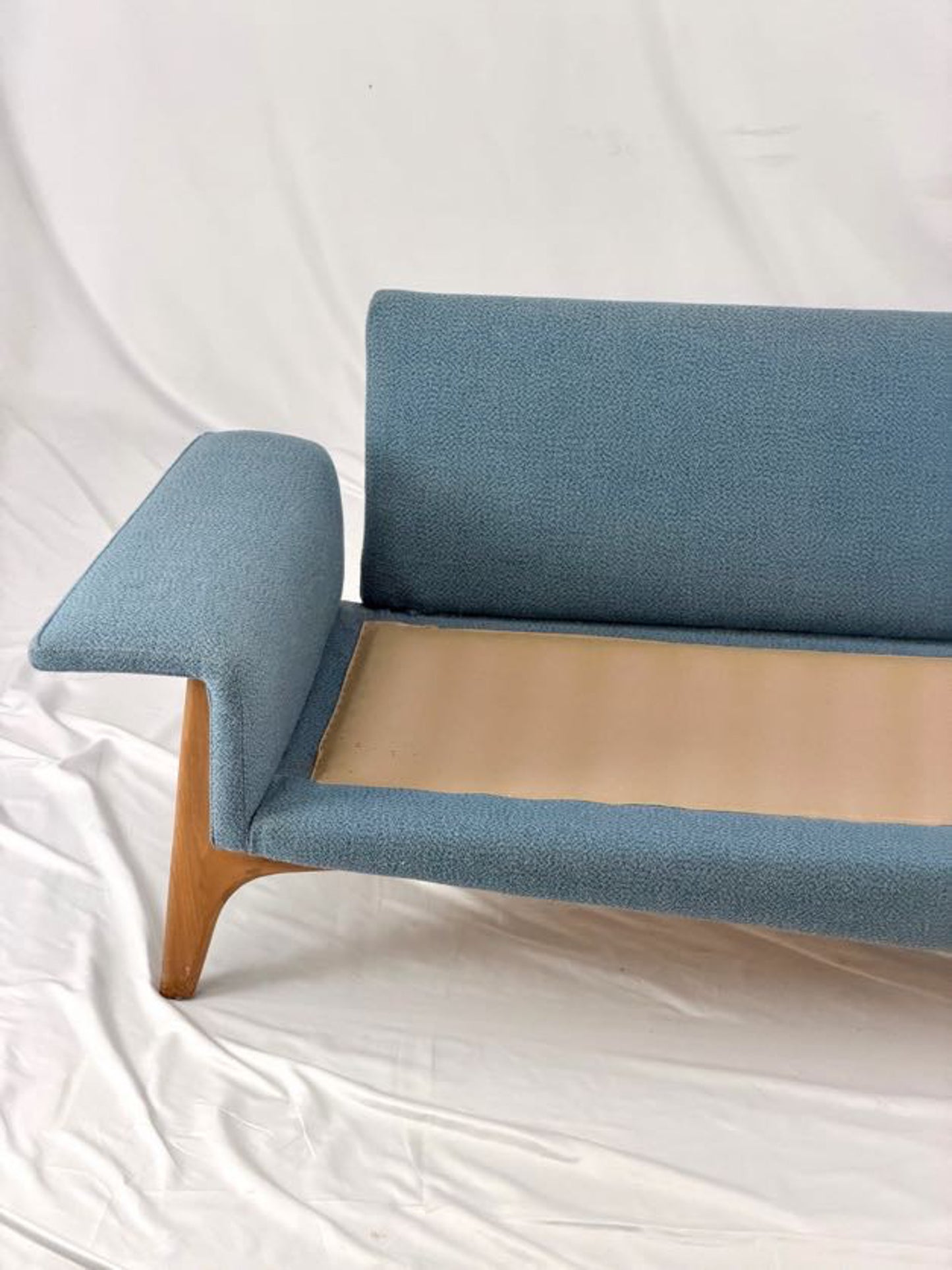 Blue sofa with wooden legs on a white background