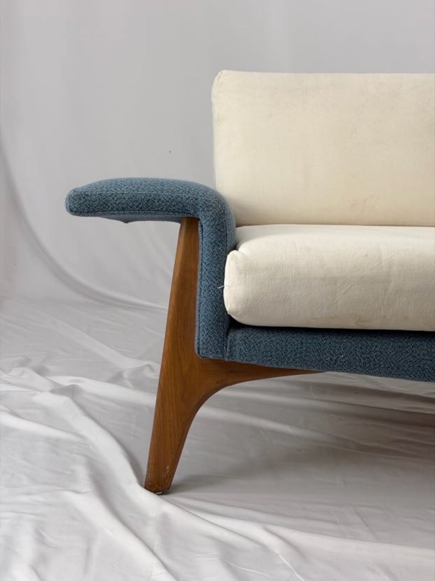 Sofa with blue armrests and beige cushions on a white background