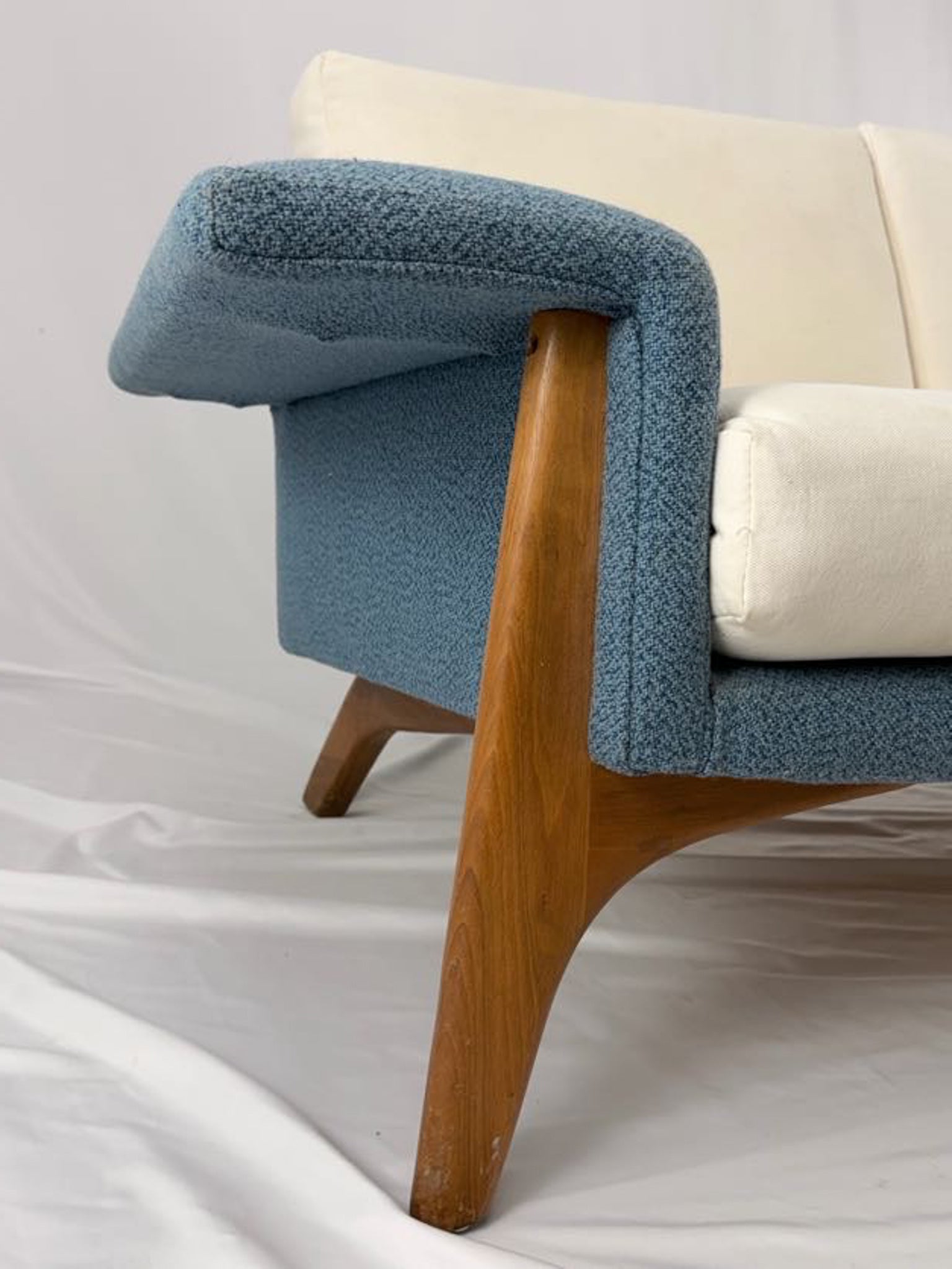 Sofa with blue armrests and beige cushions on a white background