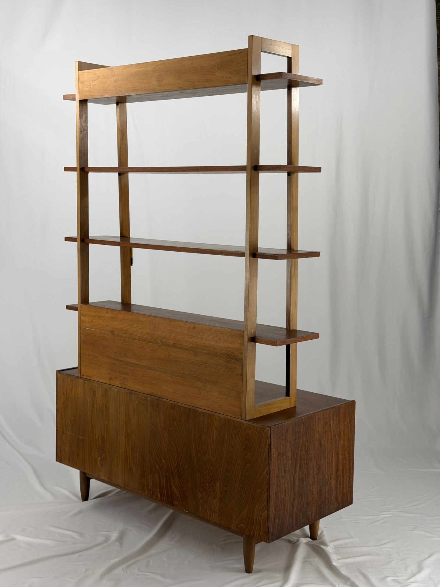 Wooden shelf unit with multiple shelves and drawers on a white background