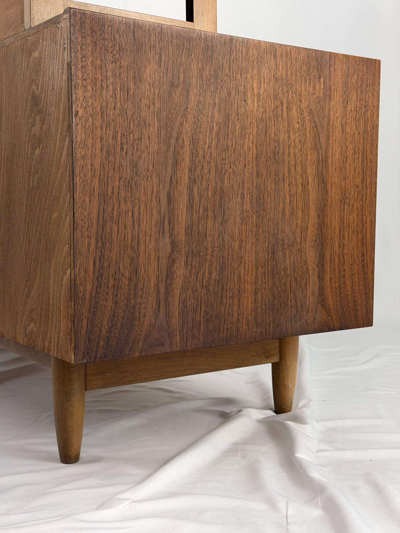 Wooden shelf unit with multiple shelves and drawers on a white background